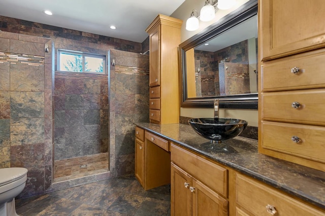 bathroom with vanity, toilet, and tiled shower