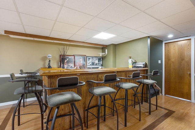 bar with a paneled ceiling and light wood-type flooring