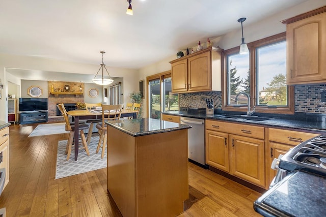 kitchen featuring backsplash, sink, stainless steel dishwasher, decorative light fixtures, and a kitchen island