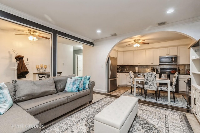 living room with ceiling fan and ornamental molding