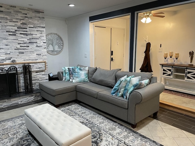 living room featuring tile patterned floors, ceiling fan, crown molding, and a tiled fireplace