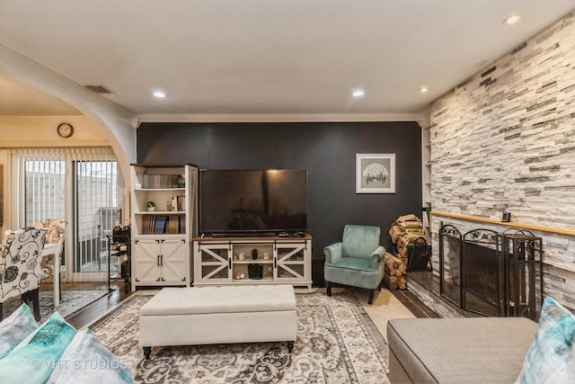 living room with light hardwood / wood-style floors, a stone fireplace, and crown molding