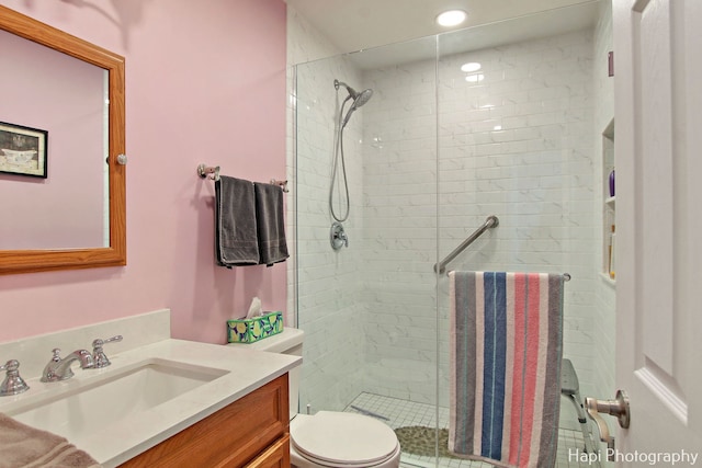 bathroom featuring a tile shower, vanity, and toilet