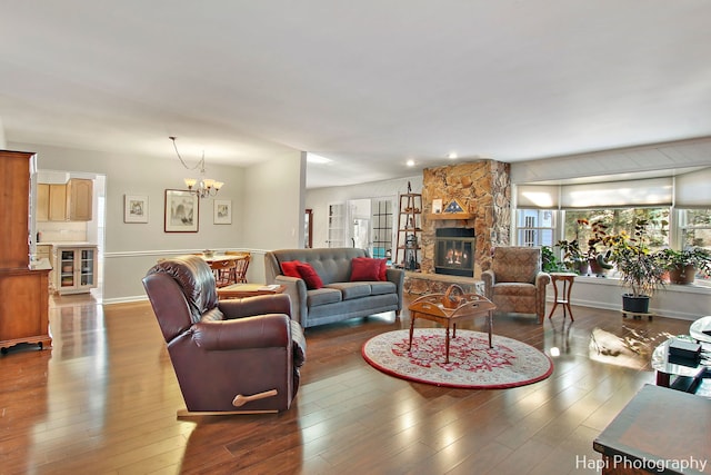 living room with a stone fireplace, hardwood / wood-style flooring, and a notable chandelier