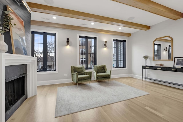 unfurnished room featuring beamed ceiling, light hardwood / wood-style flooring, and a wealth of natural light