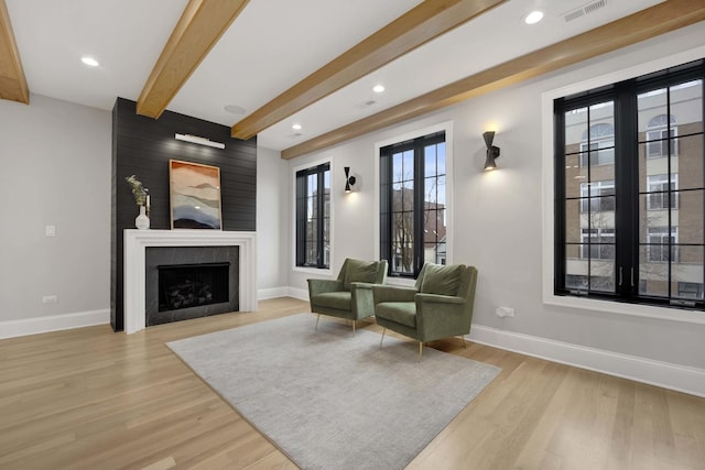 sitting room featuring beamed ceiling, light wood-type flooring, and a fireplace