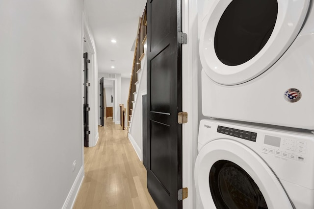 clothes washing area with stacked washer / drying machine and light wood-type flooring