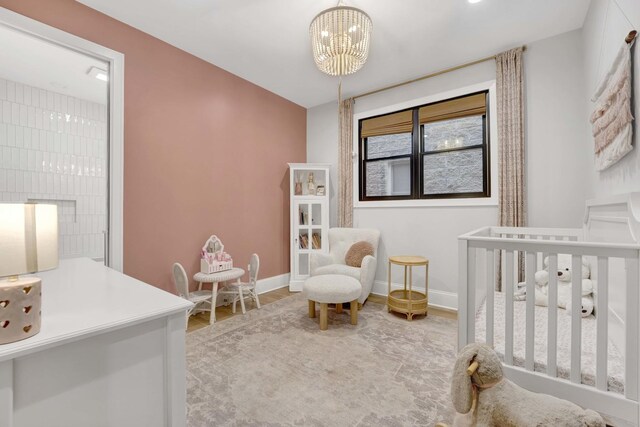 bedroom with light hardwood / wood-style flooring, a crib, and a chandelier