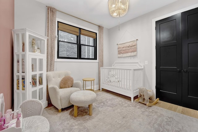 bedroom featuring an inviting chandelier, wood-type flooring, and a crib