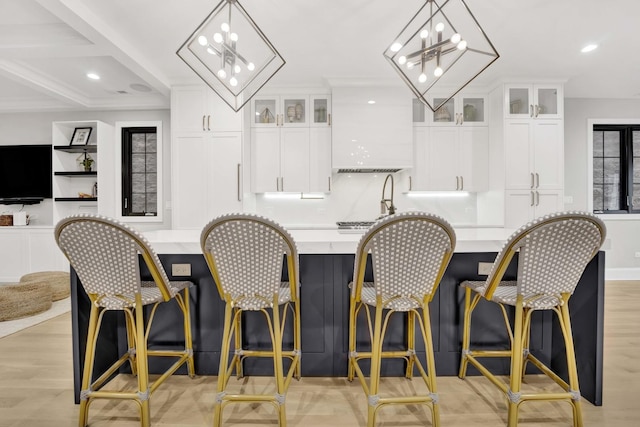 bar featuring white cabinetry, decorative light fixtures, a chandelier, and light hardwood / wood-style flooring