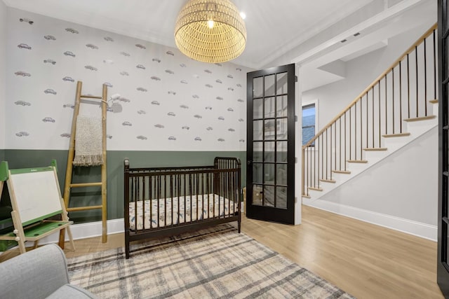 bedroom featuring wood-type flooring, ornamental molding, and a chandelier