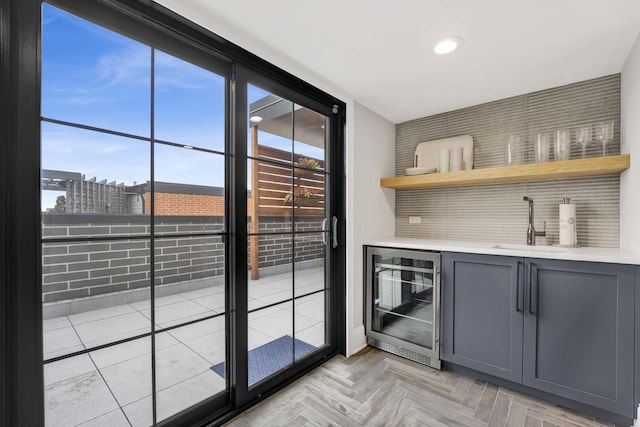 bar featuring gray cabinetry, beverage cooler, sink, and light parquet floors