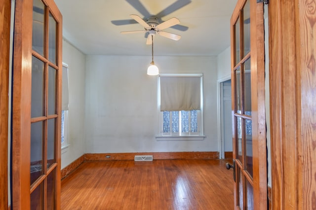 empty room featuring ceiling fan, wood-type flooring, and french doors