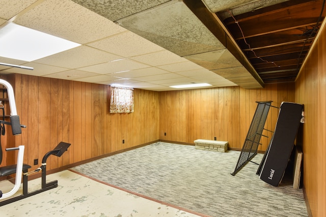 exercise room featuring a paneled ceiling and wood walls