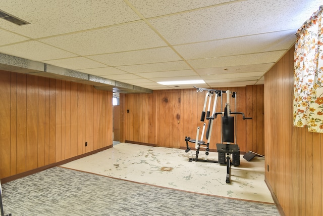 exercise area with a drop ceiling and wooden walls