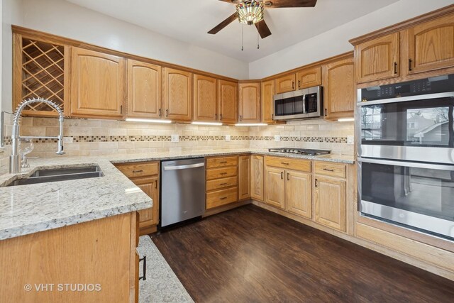 kitchen featuring lofted ceiling with skylight, sink, light stone counters, hanging light fixtures, and appliances with stainless steel finishes