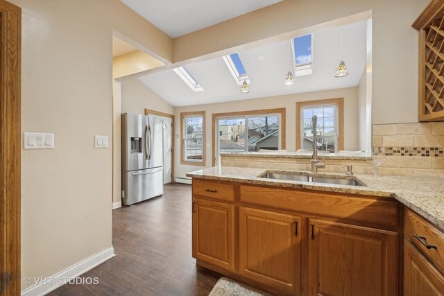 kitchen featuring sink, decorative light fixtures, vaulted ceiling, kitchen peninsula, and light stone countertops