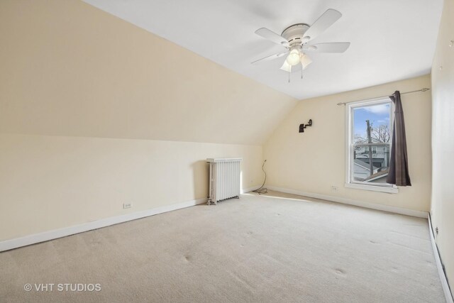 additional living space featuring light carpet, radiator heating unit, ceiling fan, and vaulted ceiling