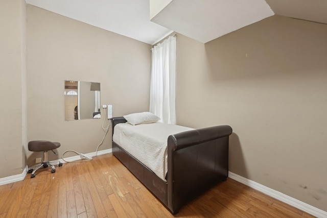 bedroom featuring multiple windows, vaulted ceiling, and hardwood / wood-style floors