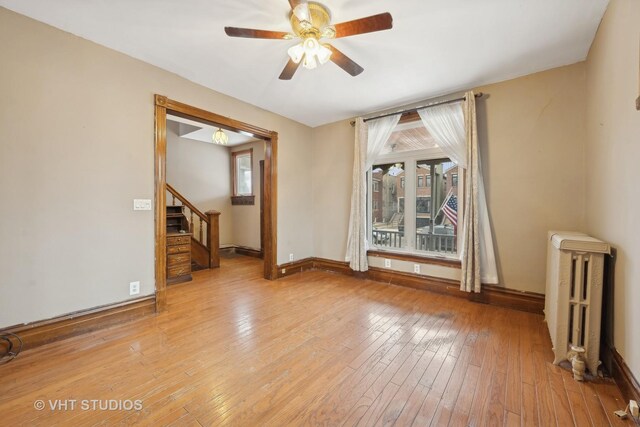 spare room featuring radiator, light hardwood / wood-style floors, and ceiling fan