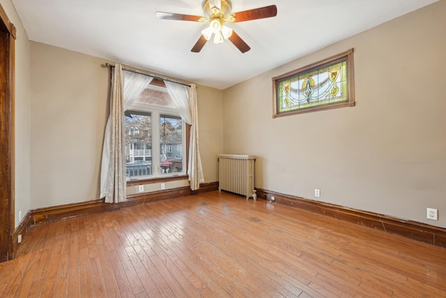 unfurnished room with ceiling fan, radiator, and light hardwood / wood-style floors