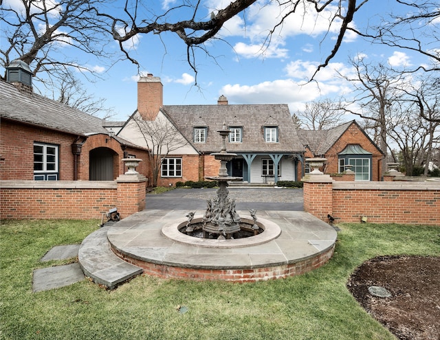 exterior space featuring a chimney, a lawn, and brick siding