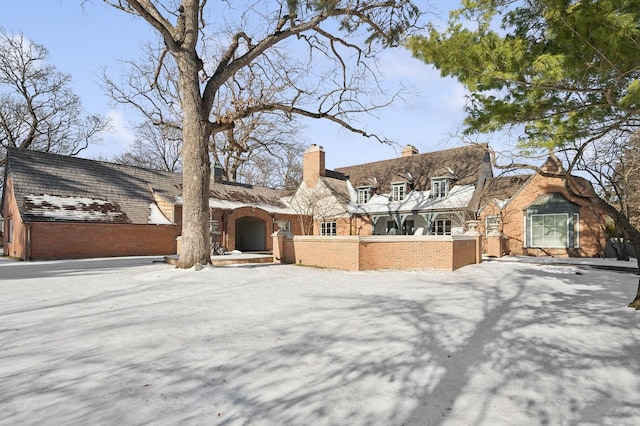 view of front facade with a fenced front yard, brick siding, and a chimney