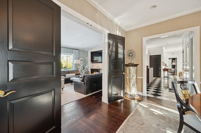 entryway with a large fireplace, baseboards, crown molding, and wood finished floors