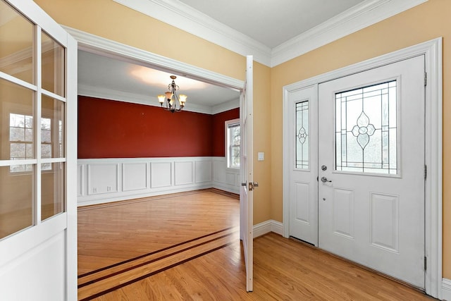 foyer with hardwood / wood-style floors, ornamental molding, and a notable chandelier