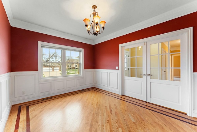 empty room featuring light hardwood / wood-style floors, ornamental molding, and an inviting chandelier