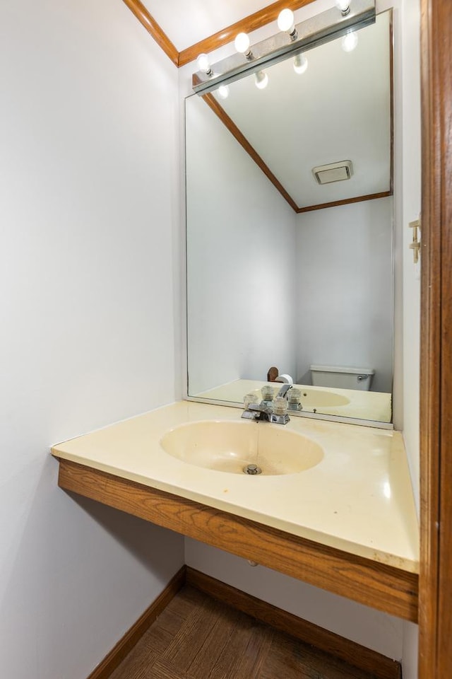 bathroom with toilet, ornamental molding, and sink