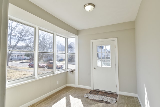 doorway featuring carpet floors and baseboards