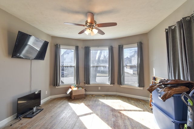 interior space with ceiling fan, hardwood / wood-style flooring, and baseboards