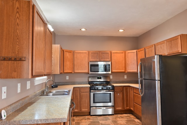 kitchen featuring brown cabinets, stainless steel appliances, recessed lighting, light countertops, and a sink