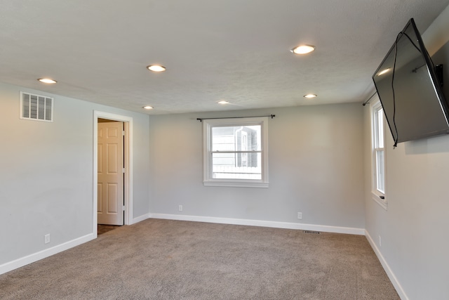 empty room with carpet flooring, visible vents, and baseboards