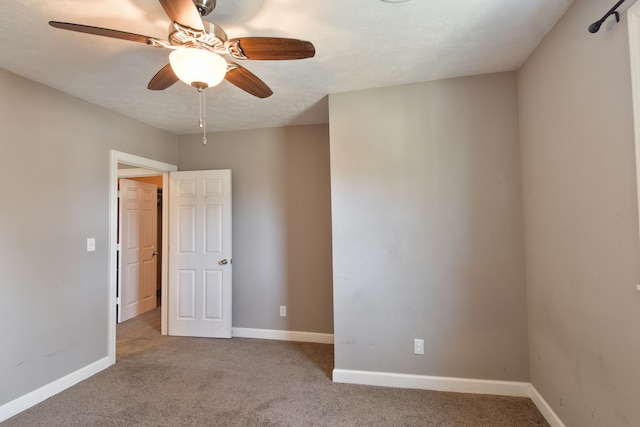 empty room with carpet floors, a ceiling fan, and baseboards