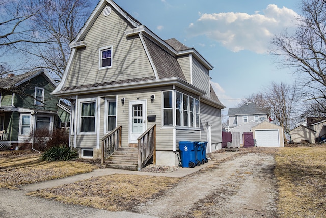 view of front of house featuring dirt driveway, a gambrel roof, entry steps, a garage, and an outdoor structure