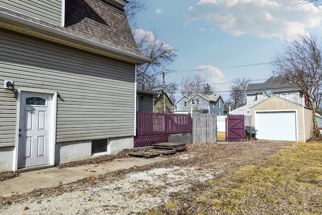 view of property exterior with an outbuilding, a garage, a shingled roof, fence, and a wooden deck