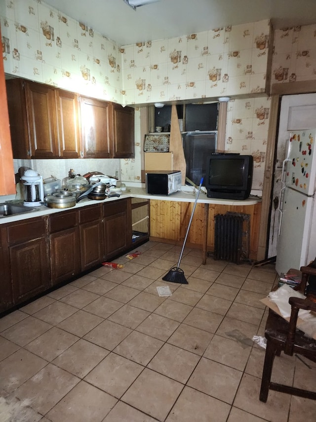 kitchen featuring light tile patterned floors, light countertops, freestanding refrigerator, and wallpapered walls