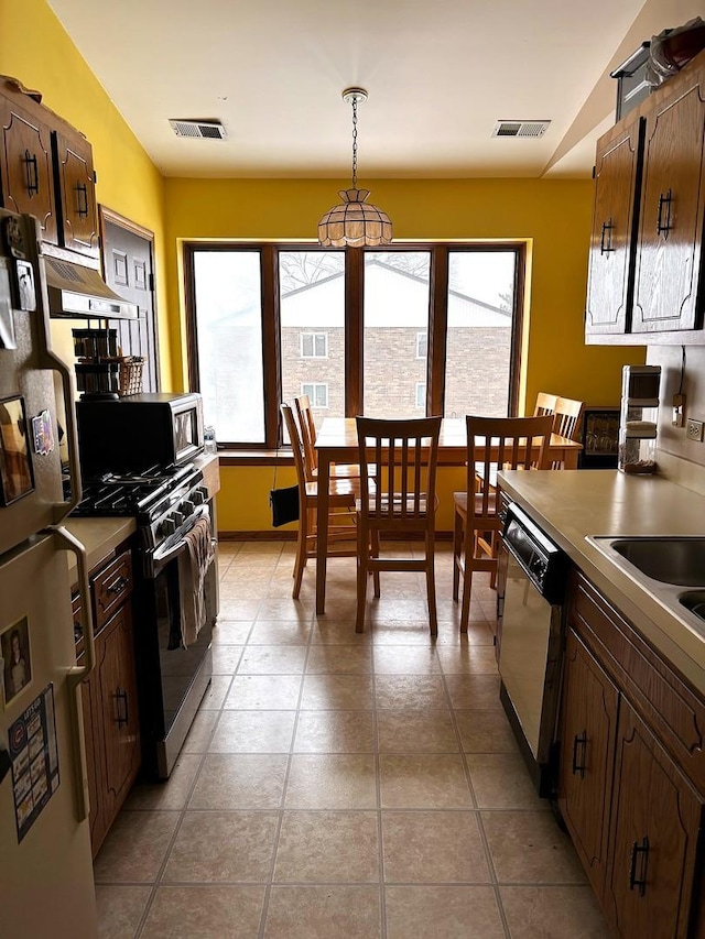 kitchen with pendant lighting, plenty of natural light, light tile patterned floors, and appliances with stainless steel finishes