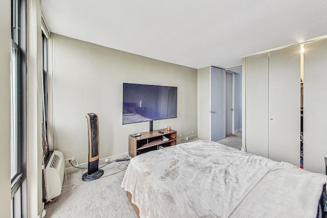 bedroom with light colored carpet, a textured ceiling, and a wall unit AC