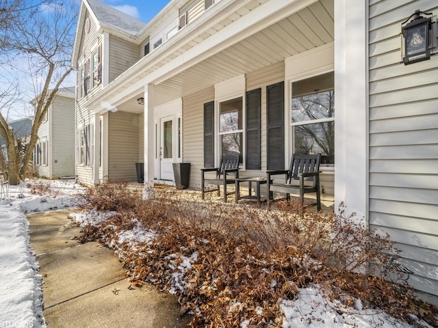 snow covered property entrance featuring covered porch