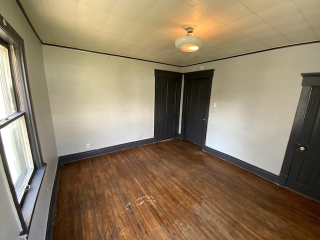 spare room with dark wood-type flooring and ornamental molding