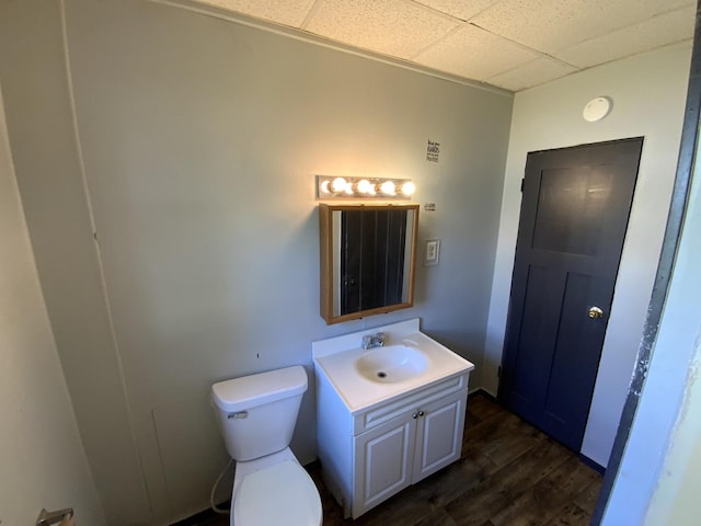 bathroom with vanity, a paneled ceiling, hardwood / wood-style flooring, and toilet