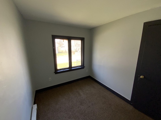 carpeted empty room with a baseboard heating unit