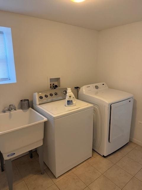 clothes washing area with sink, washer and dryer, and light tile patterned flooring