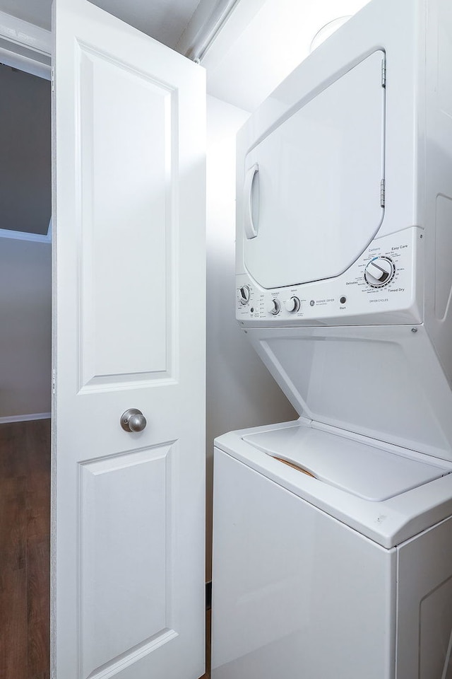 laundry room featuring stacked washer and dryer and dark hardwood / wood-style flooring