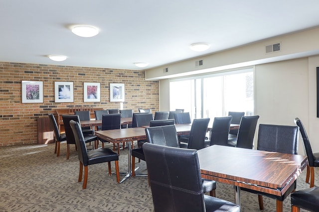 dining area featuring carpet floors and brick wall