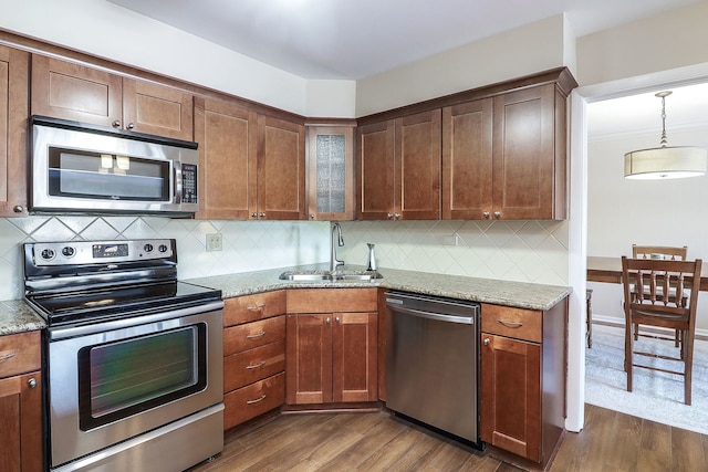 kitchen featuring light stone countertops, appliances with stainless steel finishes, dark hardwood / wood-style floors, and sink