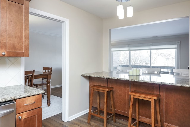 kitchen featuring dark hardwood / wood-style flooring, decorative backsplash, light stone counters, and hanging light fixtures